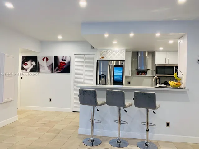 a kitchen with stainless steel appliances kitchen island granite countertop a refrigerator and a stove top oven