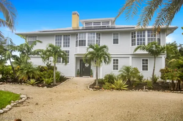a front view of a house with a yard and potted plants