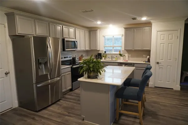 a kitchen with stainless steel appliances granite countertop a refrigerator a stove a sink a microwave and island