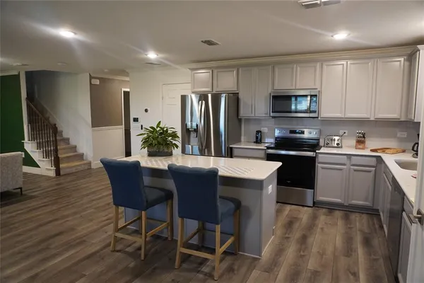 a kitchen with a table chairs microwave and refrigerator