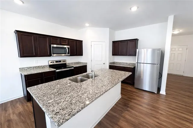 a kitchen with stainless steel appliances wooden floor and a refrigerator