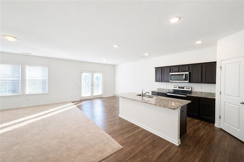 5075 Minnow Lane Cumming, GA 30028 - Photo 7 of 31 a large kitchen with stainless steel appliances granite countertop a stove a sink and a microwave