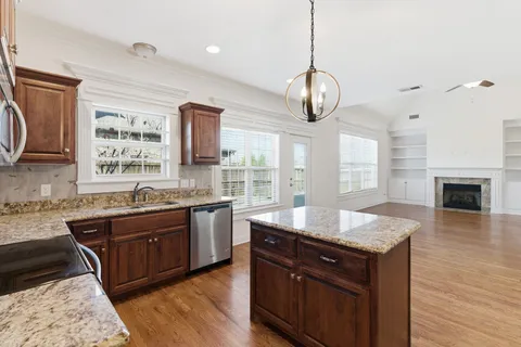 a large kitchen with granite countertop a stove a sink and a wooden floors
