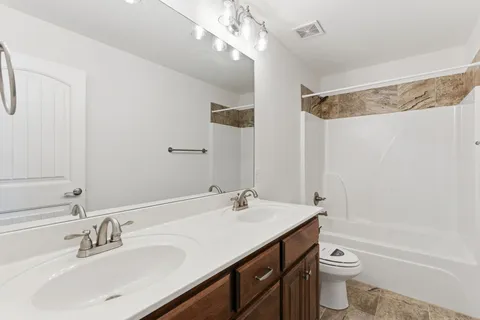 a bathroom with a sink a toilet a mirror and shower