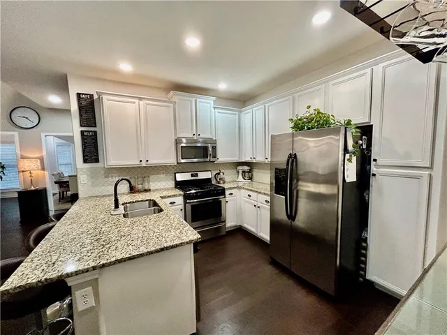 a kitchen with a refrigerator a microwave a sink and cabinets