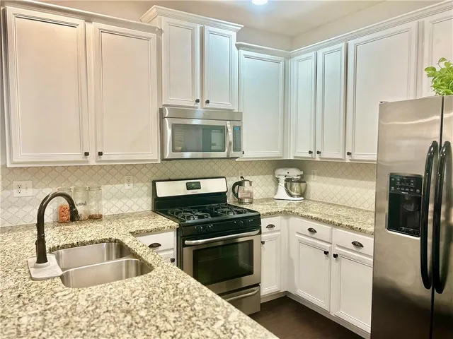 a kitchen with granite countertop a sink stainless steel appliances and cabinets