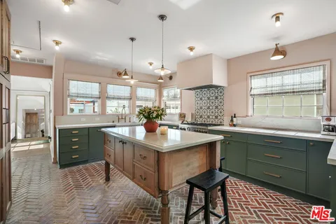 a kitchen with kitchen island granite countertop a sink and a stove
