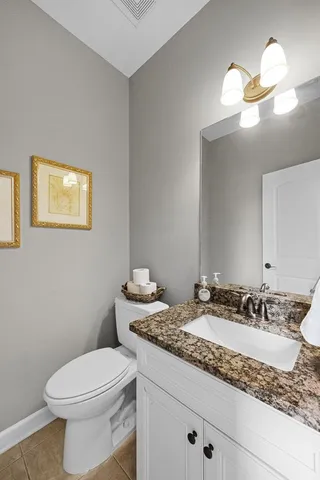 a bathroom with a granite countertop toilet sink and mirror