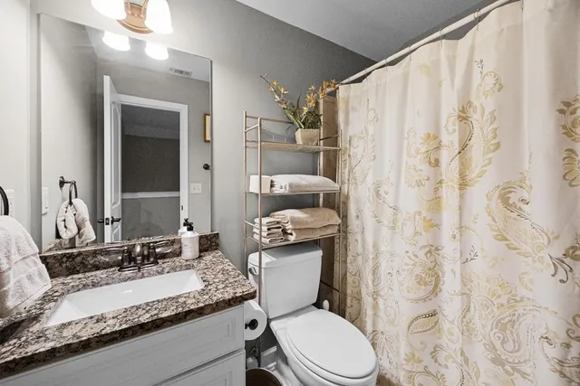 a bathroom with a granite countertop toilet sink and mirror