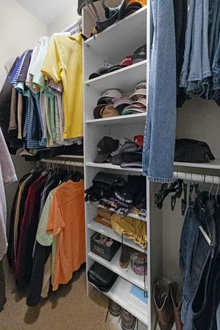 a view of walk in closet with clothes and shoes