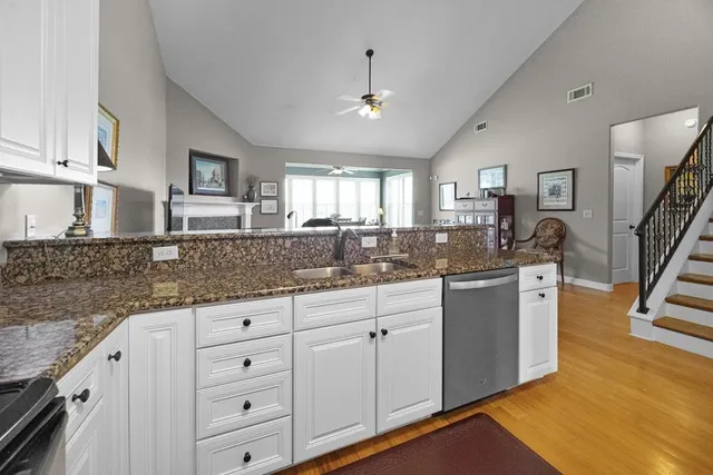 a kitchen with granite countertop a sink cabinets and wooden floor
