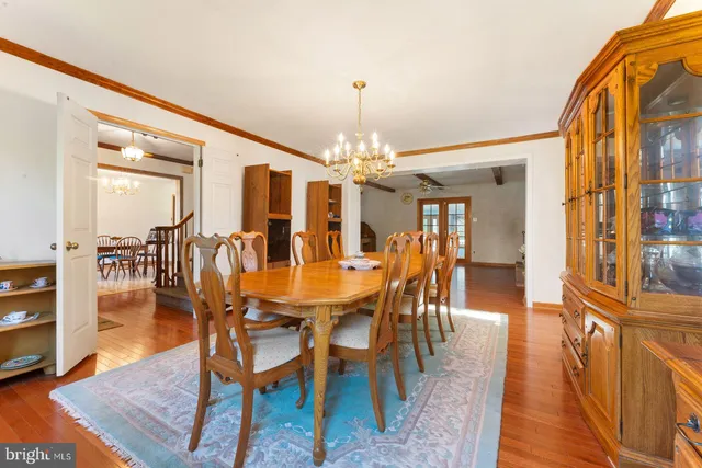 a dining room with wooden floor a chandelier a wooden table and chairs