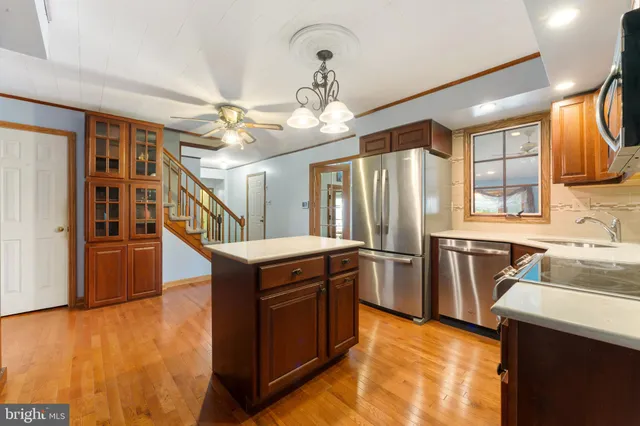 a kitchen with stainless steel appliances kitchen island granite countertop a refrigerator a stove top oven a sink and dishwasher