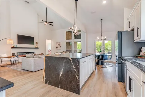 a large kitchen with stainless steel appliances a stove a sink dishwasher a oven and a dining table with wooden floor