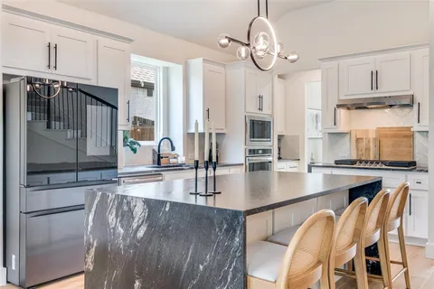 a kitchen with stainless steel appliances granite countertop a stove top oven a refrigerator a sink and white cabinets