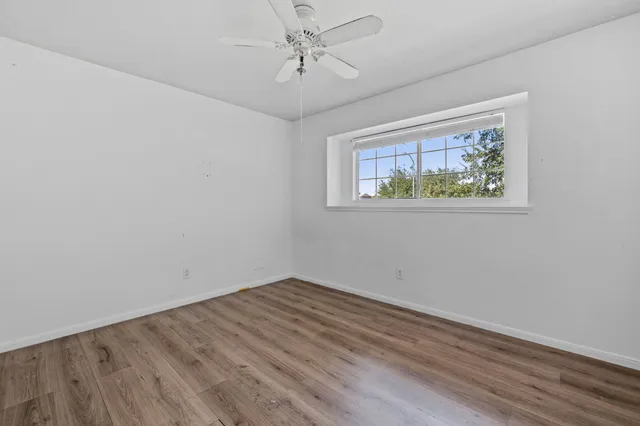 an empty room with wooden floor and ceiling fan