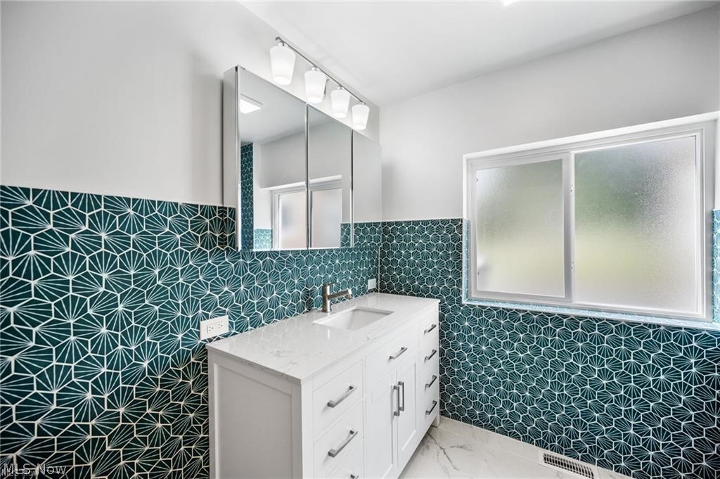 28300 Aurora Road Solon, OH 44139 - Photo 9 of 36 Bathroom featuring a white vanity with an integrated sink, polished chrome faucet, and contemporary hardware