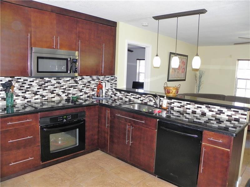 9650 Colorado Court Boca Raton, FL 33434 - Photo 3 of 14 a kitchen with stainless steel appliances wooden cabinets and a stove top oven