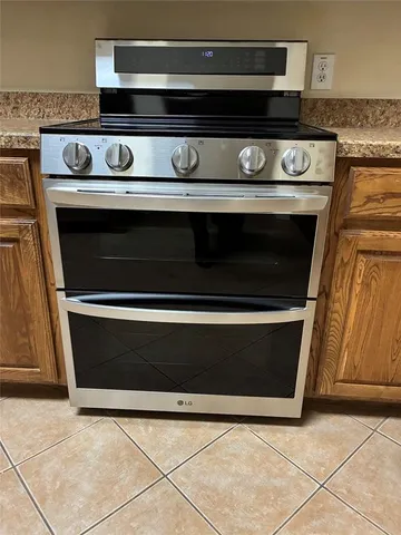 a kitchen with stainless steel appliances granite countertop a refrigerator a stove and a sink with wooden cabinets