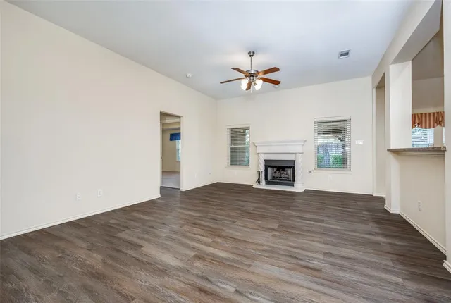 an empty room with chandelier fan and windows