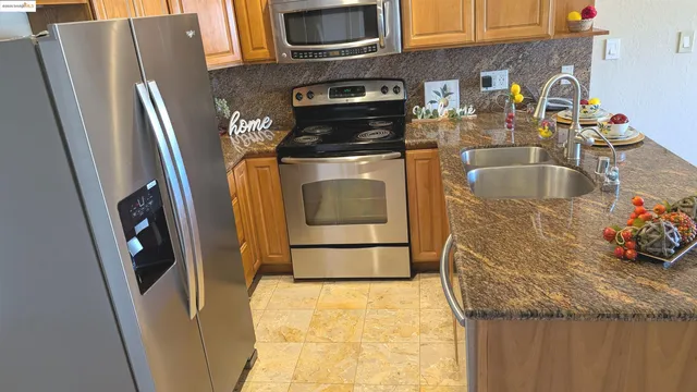 a kitchen with stainless steel appliances granite countertop a refrigerator a stove and a sink