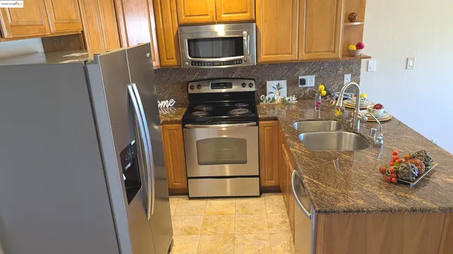 a kitchen with granite countertop a refrigerator stove and sink