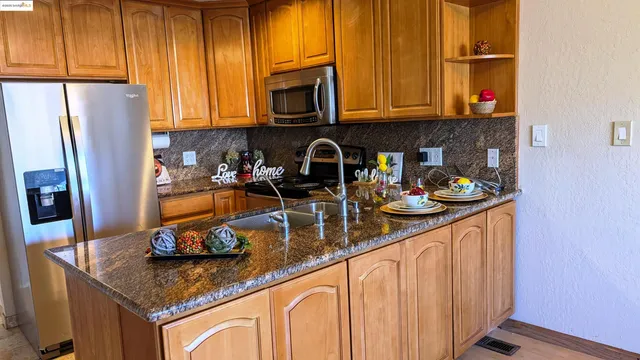 a kitchen with stainless steel appliances granite countertop a refrigerator and a stove top oven