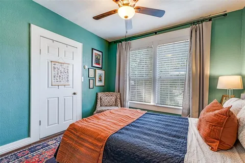 a bedroom with a bed and a lamp on dresser next to a window