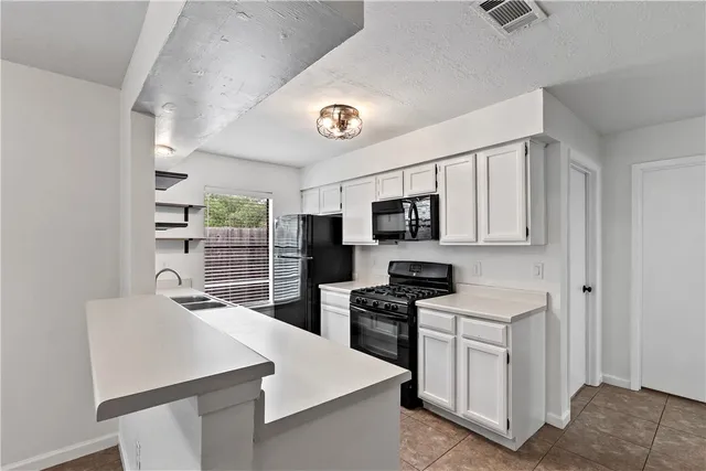 a kitchen with white cabinets and appliances