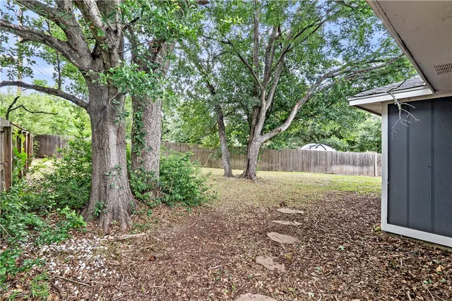 a view of backyard with large trees and plants