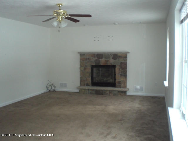 1002 Laurel Road Pocono Summit, PA 18346 - Photo 3 of 13 an empty room with a fireplace and fan