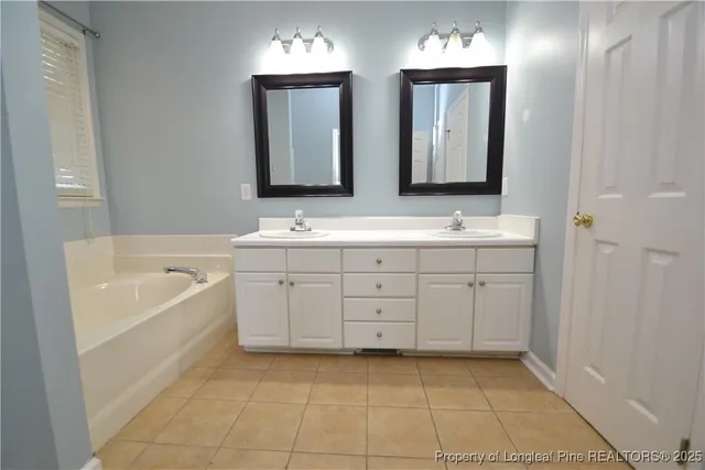 a spacious bathroom with a double vanity sink a mirror and a bathtub