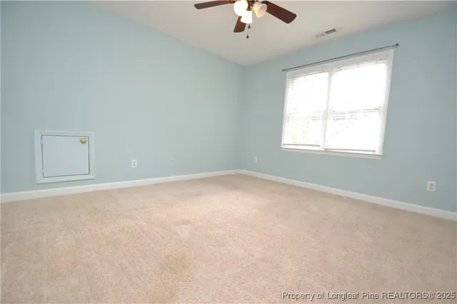 an empty room with a window and a ceiling fan
