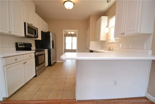 a kitchen with stainless steel appliances granite countertop a sink a stove top oven and white cabinets