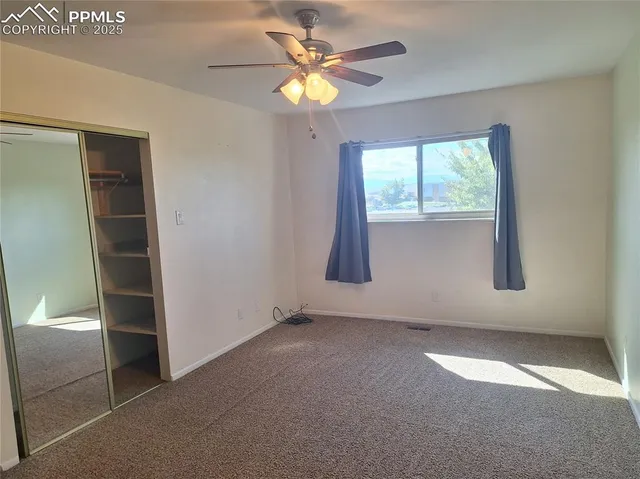 an empty room with windows and fan