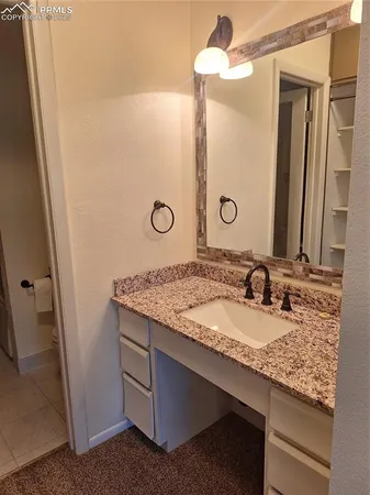 a bathroom with a granite countertop sink and a mirror