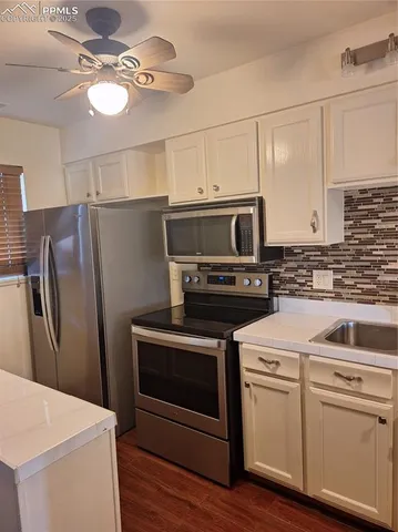 a kitchen with cabinets stainless steel appliances and wooden floor