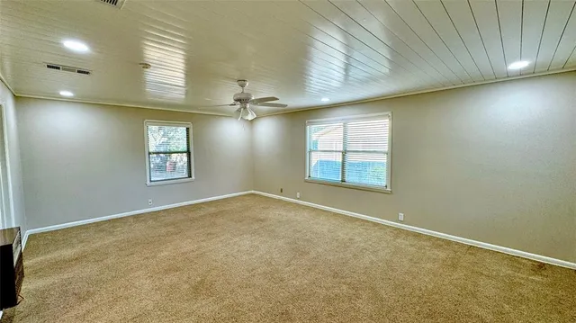 an empty room with windows and ceiling fan