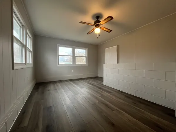 a view of an empty room with wooden floor and a window