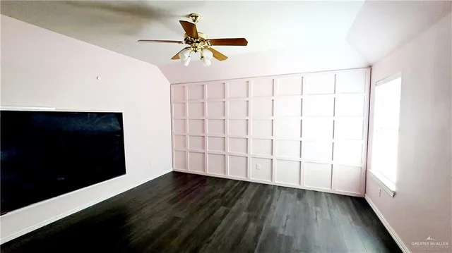 a view of empty room with wooden floor and fan