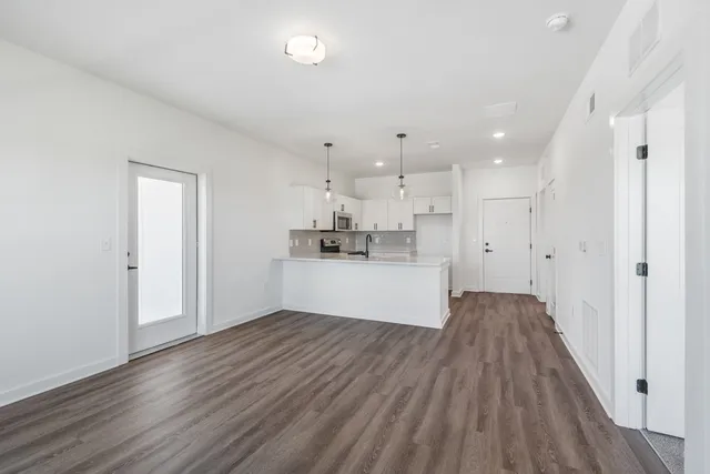 a large white kitchen with kitchen island a sink a stove and white cabinets with wooden floor