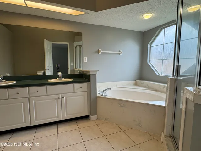 a spacious bathroom with a granite countertop sink a mirror and a bathtub