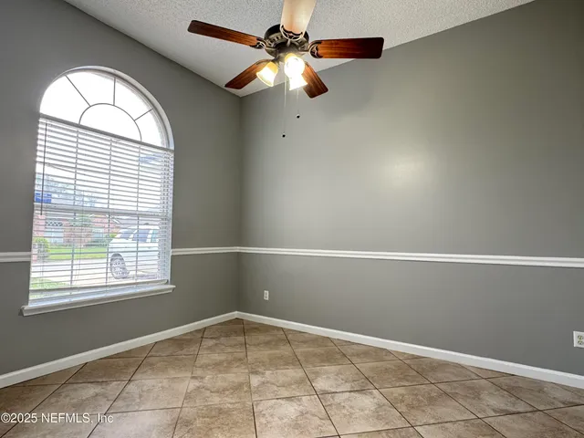 an empty room with windows and fan