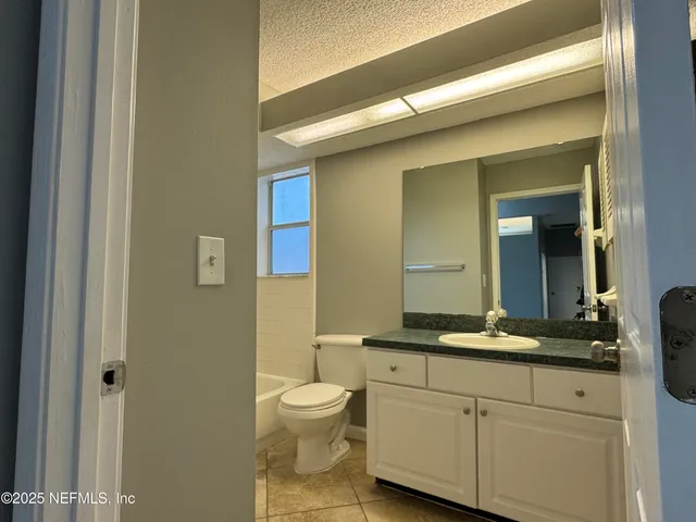 a bathroom with a granite countertop sink a toilet and mirror