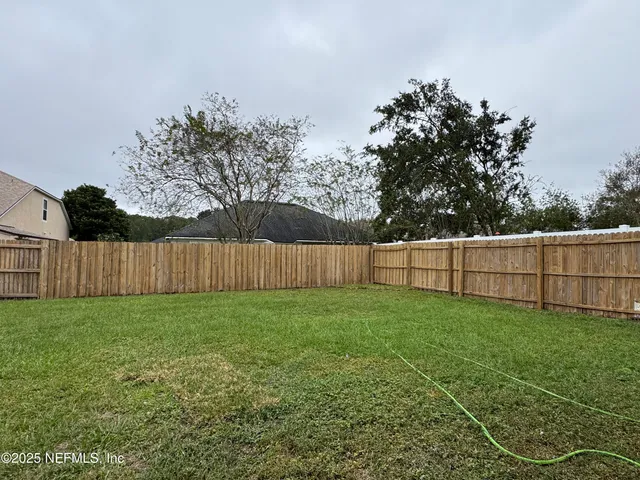 a view of a yard with wooden fence and trees
