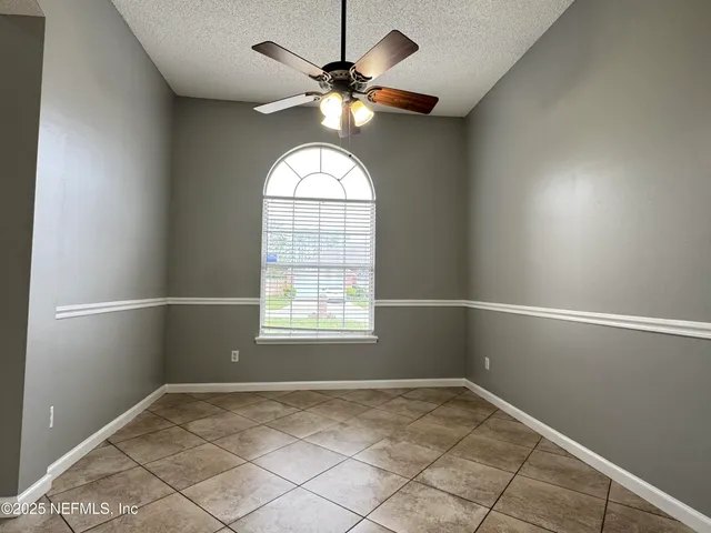 an empty room with a window and a fan