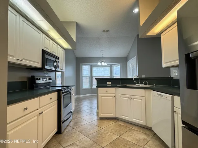 a kitchen with stainless steel appliances granite countertop a sink a stove top oven a chimney and a center island