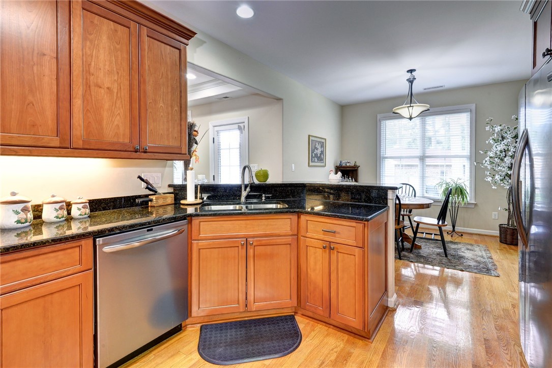 11 Butler Farm Road Hampton, VA 23666 - Photo 22 of 39 Kitchen featuring dishwasher, a peninsula, light wood-type flooring, brown cabinets, and freestanding refrigerator