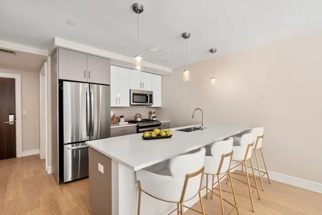 a kitchen with stainless steel appliances a refrigerator a stove a sink cabinets and a dining table