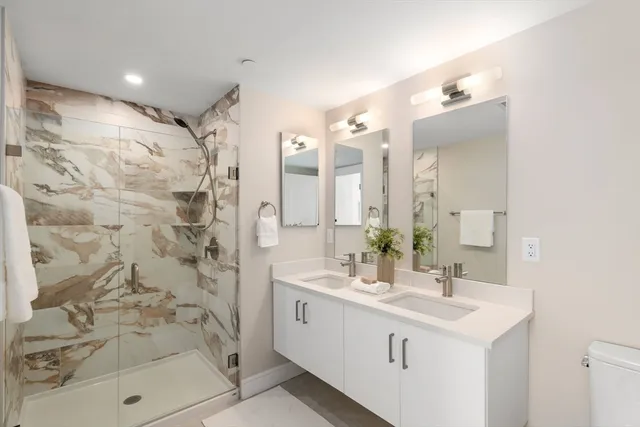 a bathroom with a double vanity sink mirror and shower